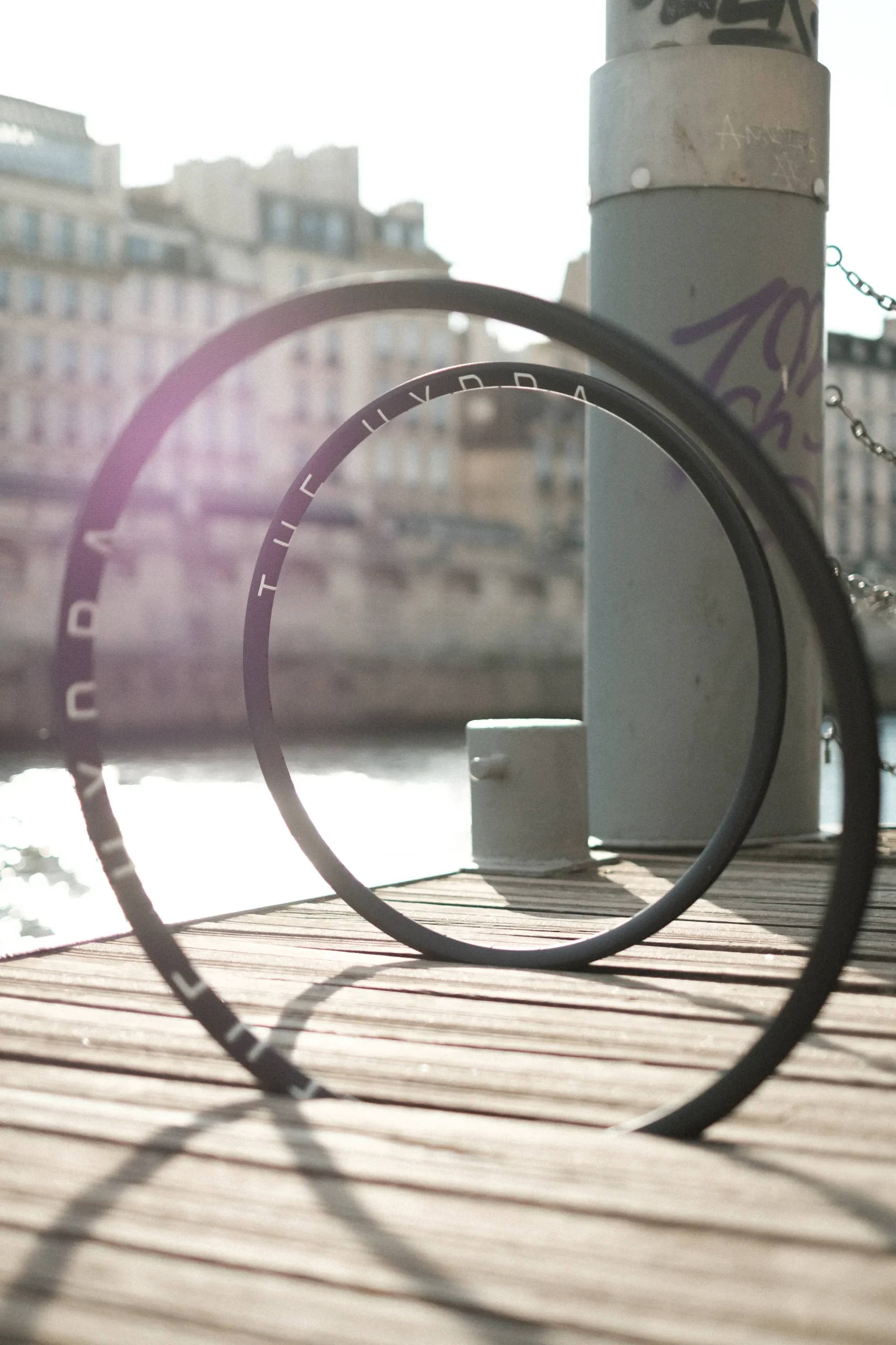 A fixed gear bicycle wheel leaning against a stone column in soft sunlight