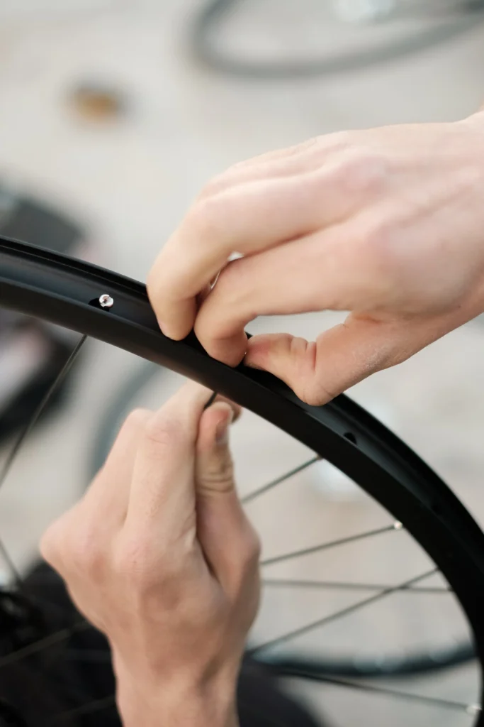 Hands fitting a spoke through a black rim.