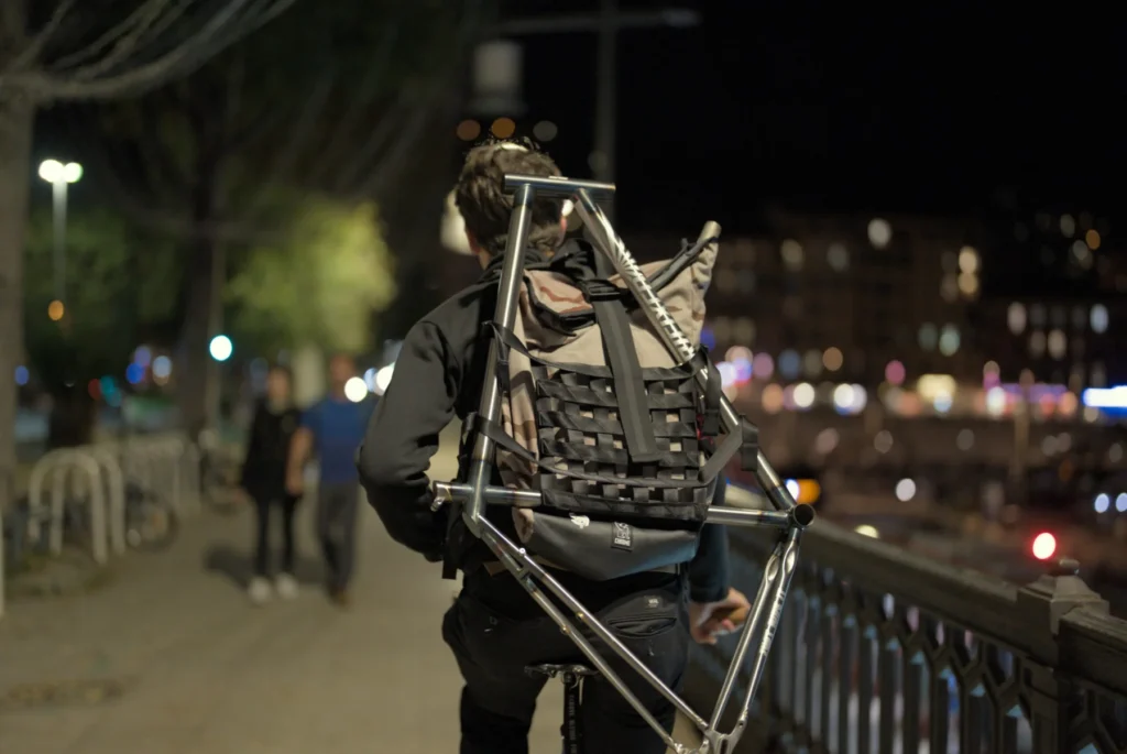El Fakijoe carrying the raw steel JRI Grit bicycle frame at night