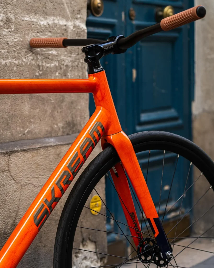 The Lava orange Skream frame and front wheel beside the blue doorway