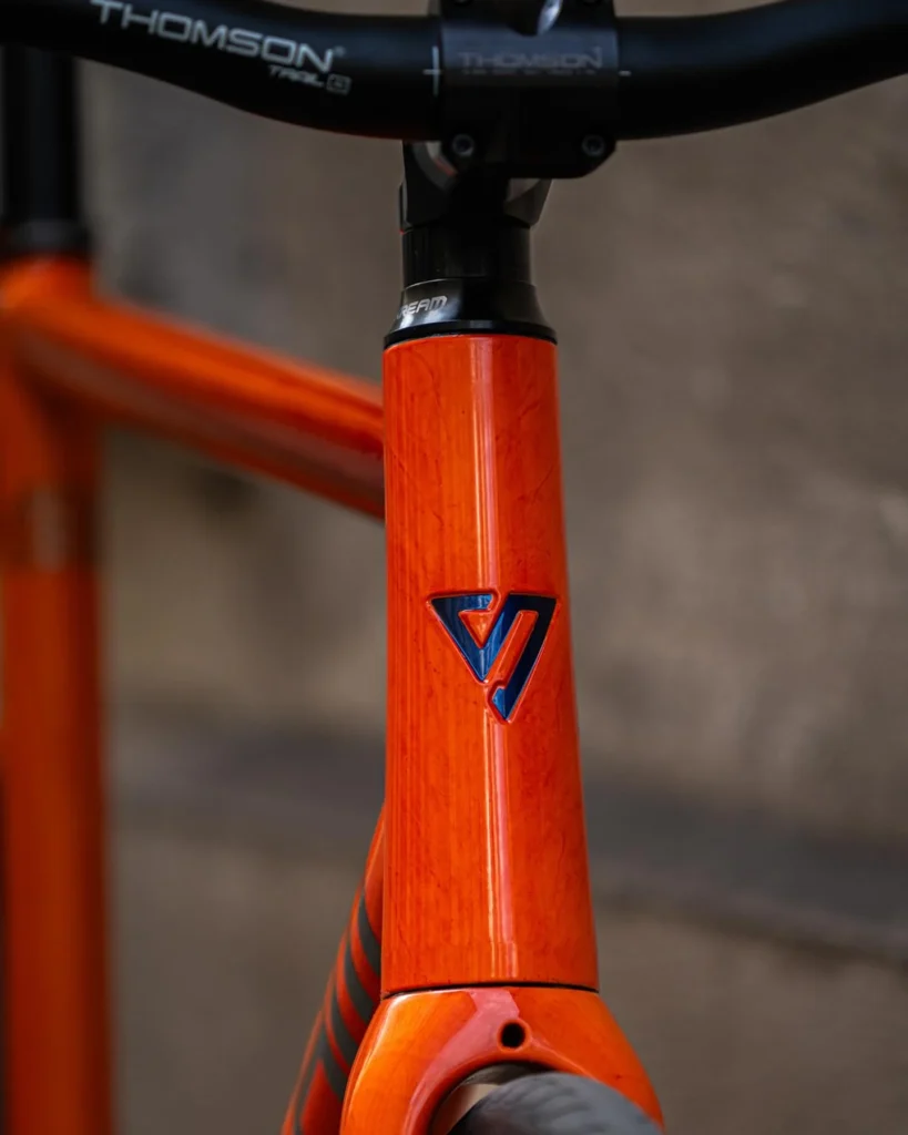 Close view of the orange Skream head tube beneath a black Thomson stem