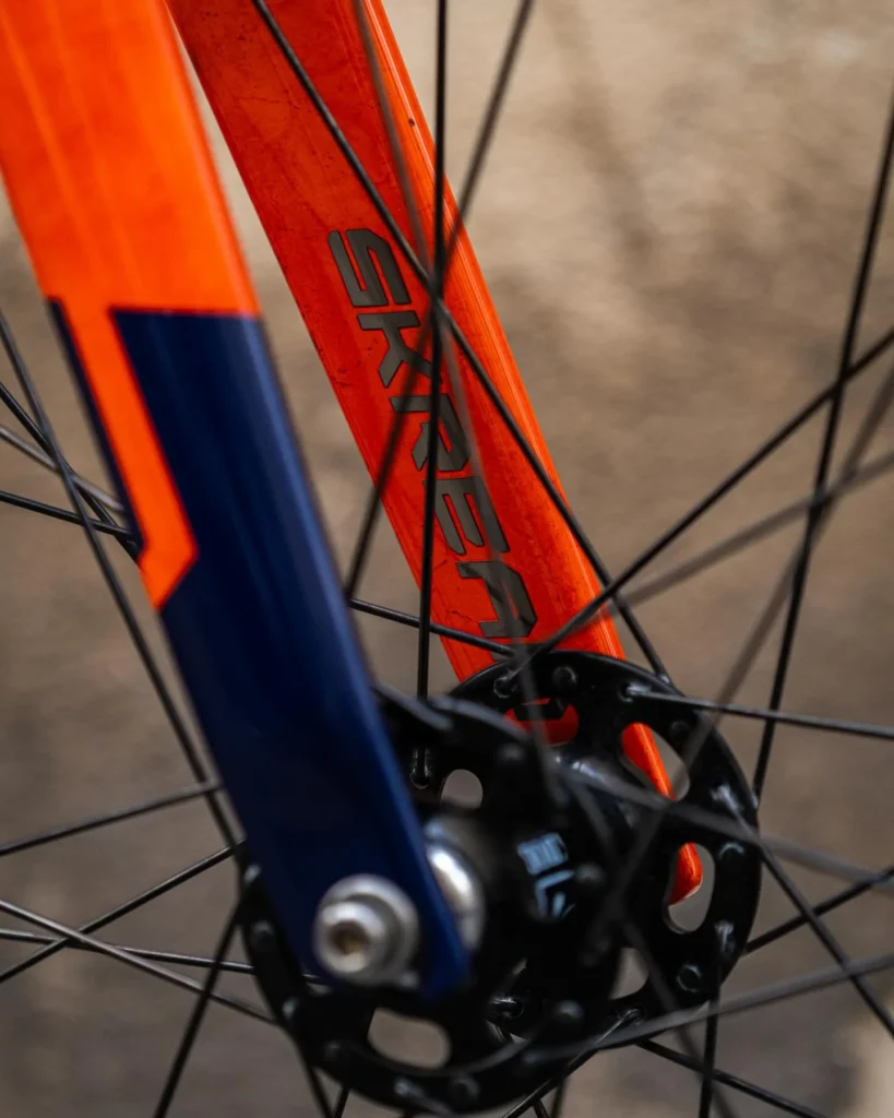 The orange and blue Skream fork around the black front hub and spokes
