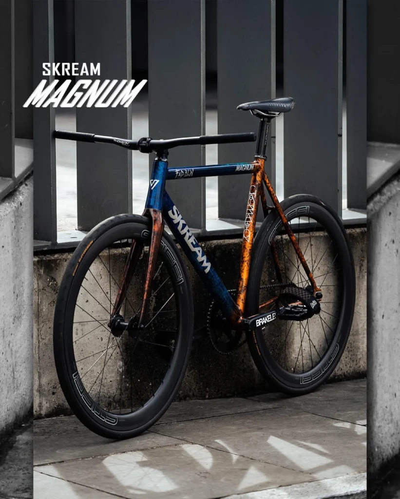 The blue and orange custom Skream Magnum bicycle against a grey metal facade