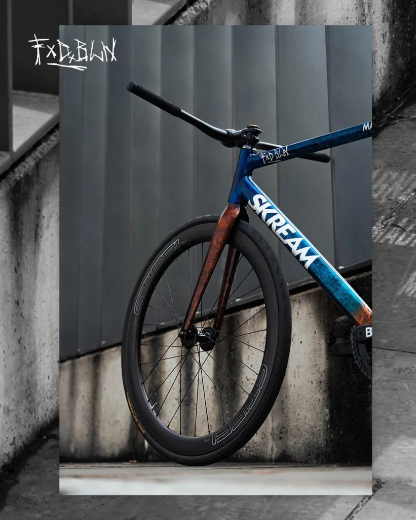 The custom blue and orange Skream Magnum leaning against a concrete wall, with an orange fork and deep front rim