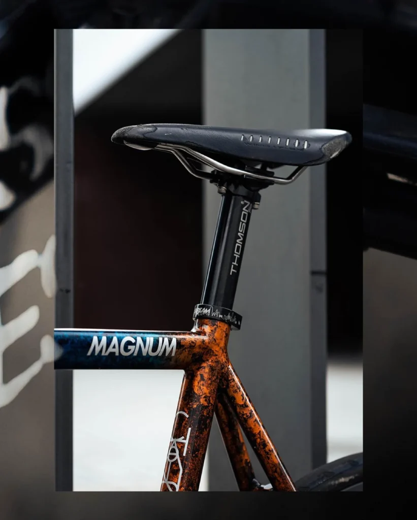 Black saddle and seatpost above the orange and blue Magnum seat tube