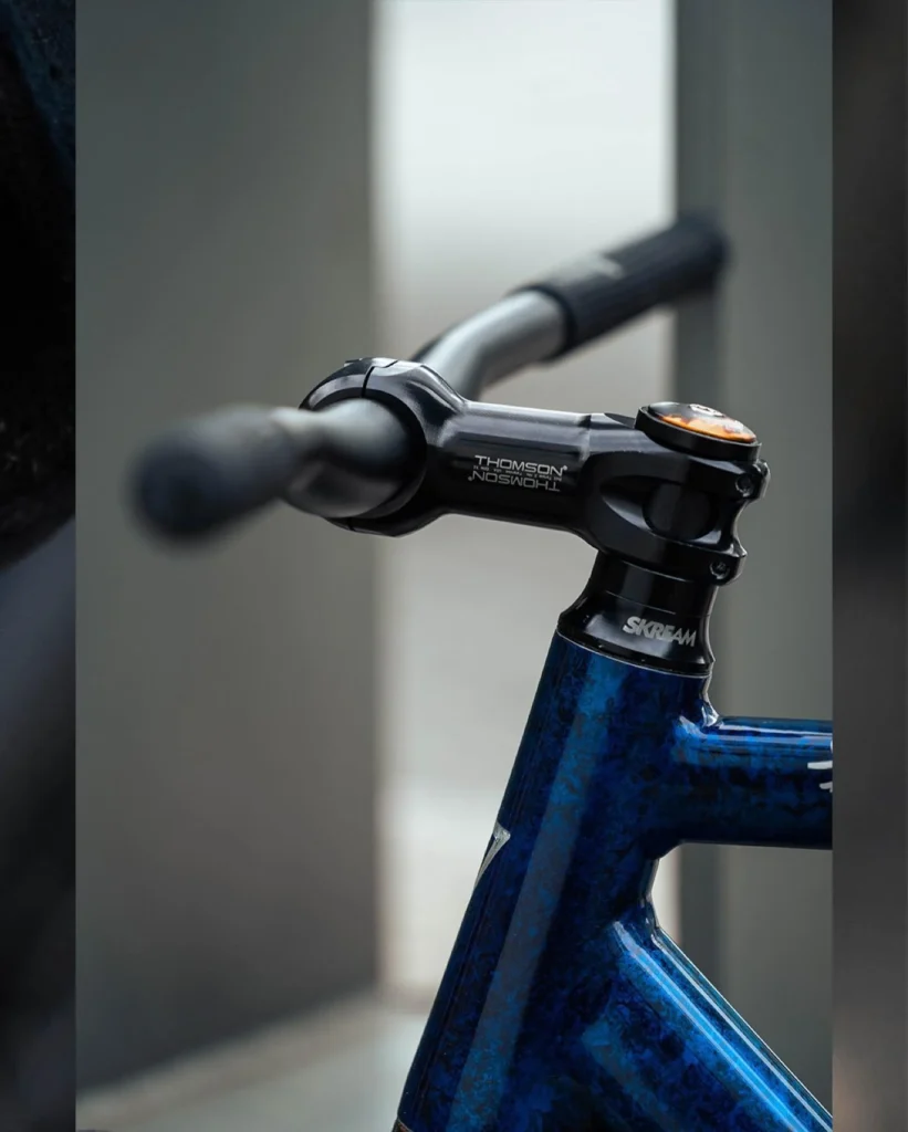 Black Thomson stem and handlebar above the blue custom frame
