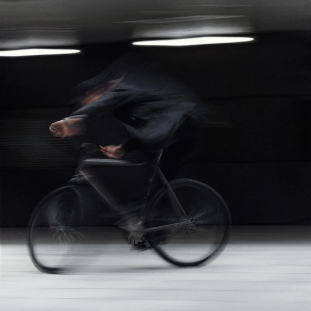 El Fakijoe and his fixed gear bicycle crossing an underground car park in a blurred motion study